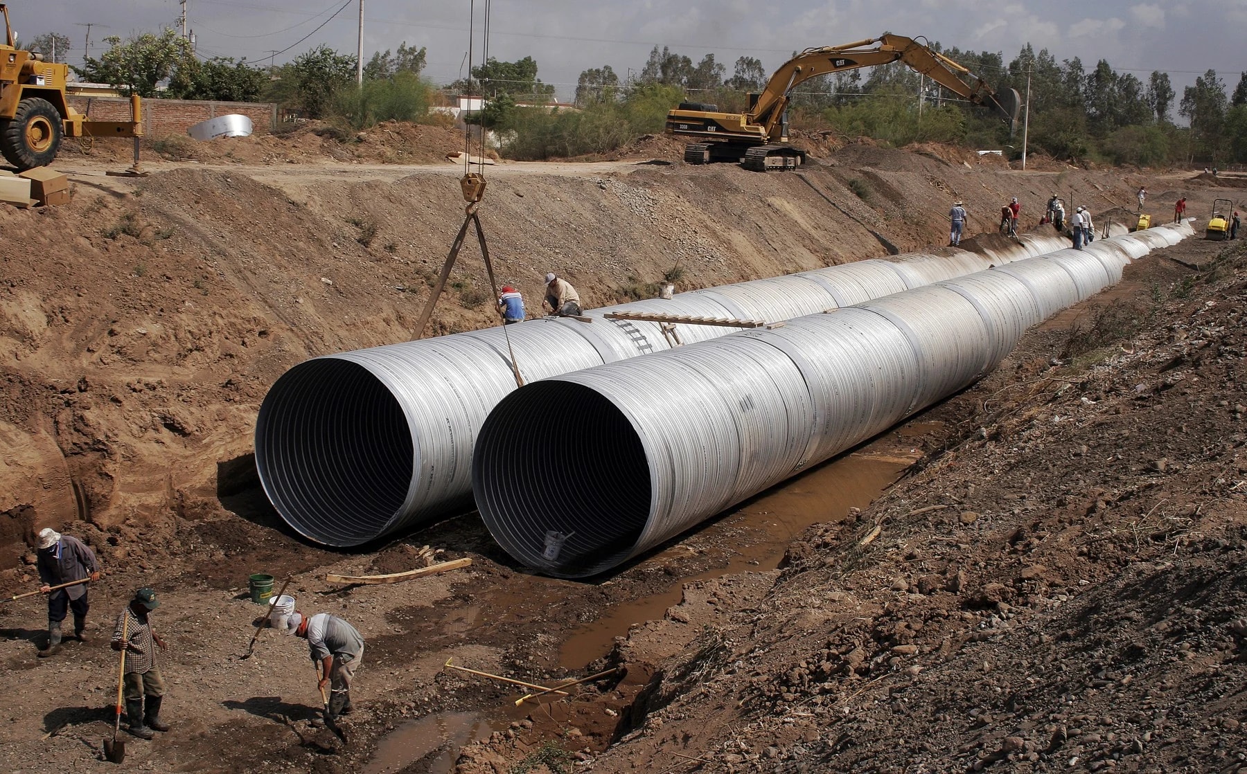 Large-diameter pipes being installed in an open trench